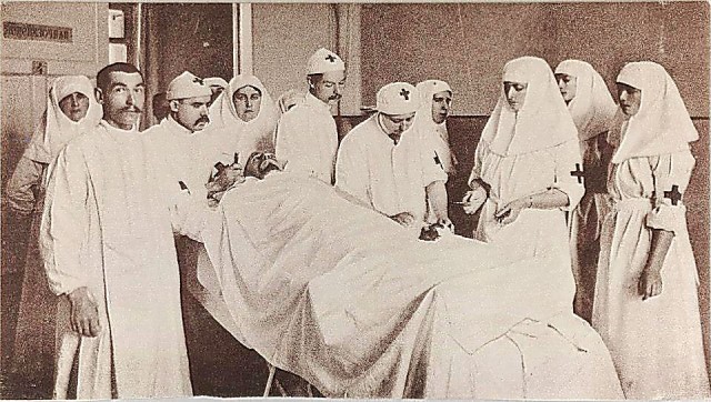 В операционной (в центре, склонившись над раненым — княжна В.И. Гедройц, справа от нее — Александра Федоровна с дочер
